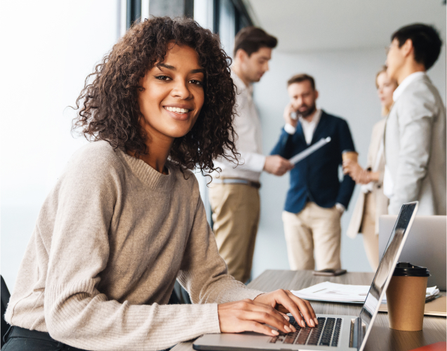 A photo of a smiling woman with a laptop.